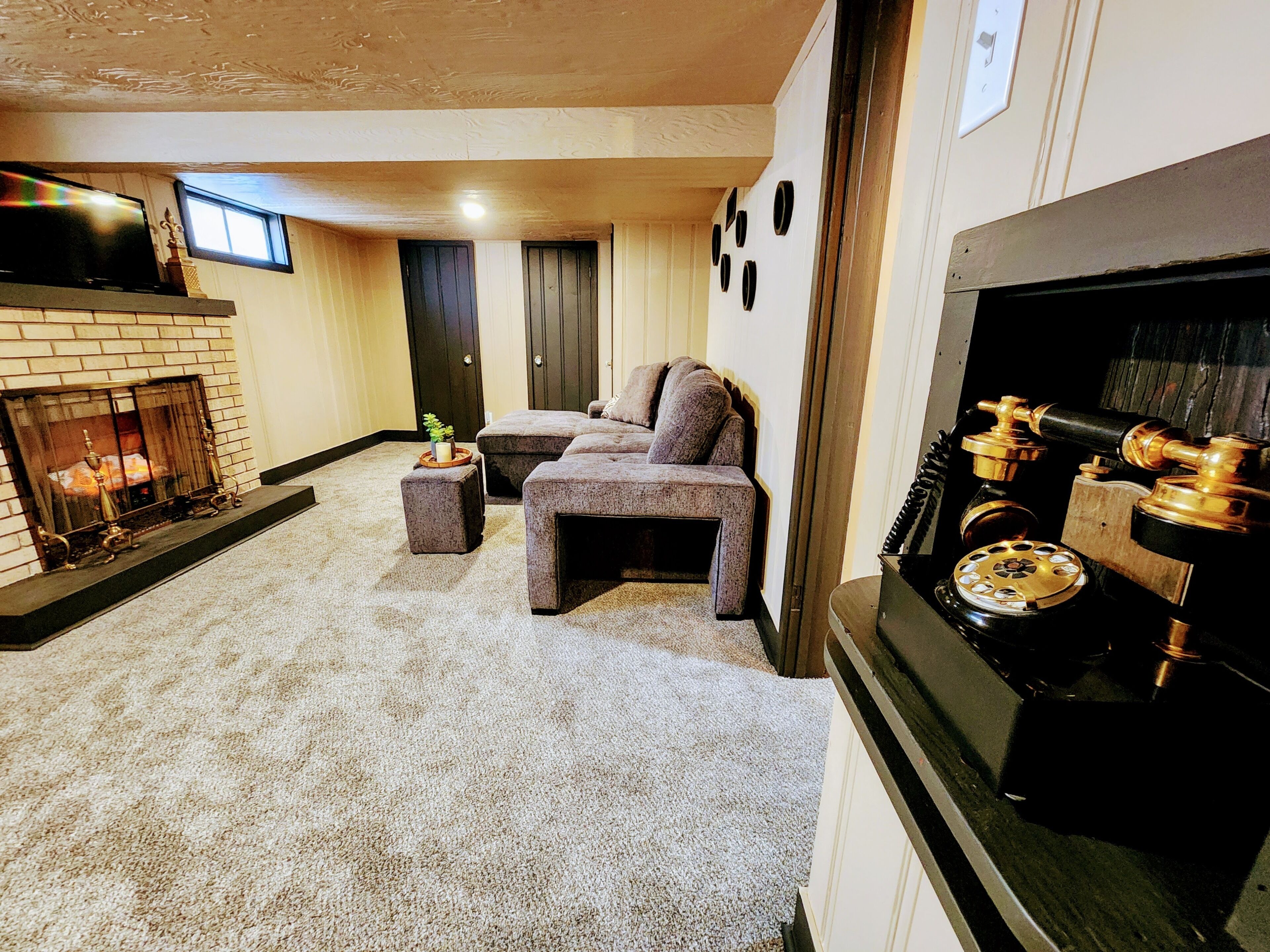 A living room with a fireplace, a sofa set, and a vintage telephone.