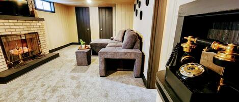 A living room with a fireplace, a sofa set, and a vintage telephone.