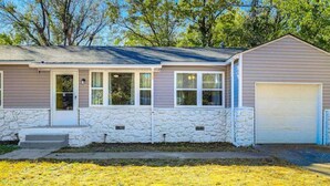 A single-story house with a stone foundation, a garage, and a front porch. - Cozy 3-Bedroom Home – Sleeps 6 (Tulsa)