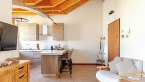 A modern kitchen with wooden cabinets, a central island, and bar stools. - [Cotton Flower] Penthouse 15 minutes from Malpensa MXP (Busto Arsizio)