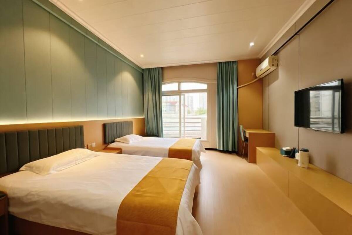 Habitación de hotel con dos camas, un televisor y una ventana con cortinas.