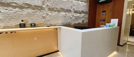 Un comptoir d’accueil avec un mur en pierre en arrière-plan, un téléviseur à écran plat et un mur recouvert de panneaux en bois.