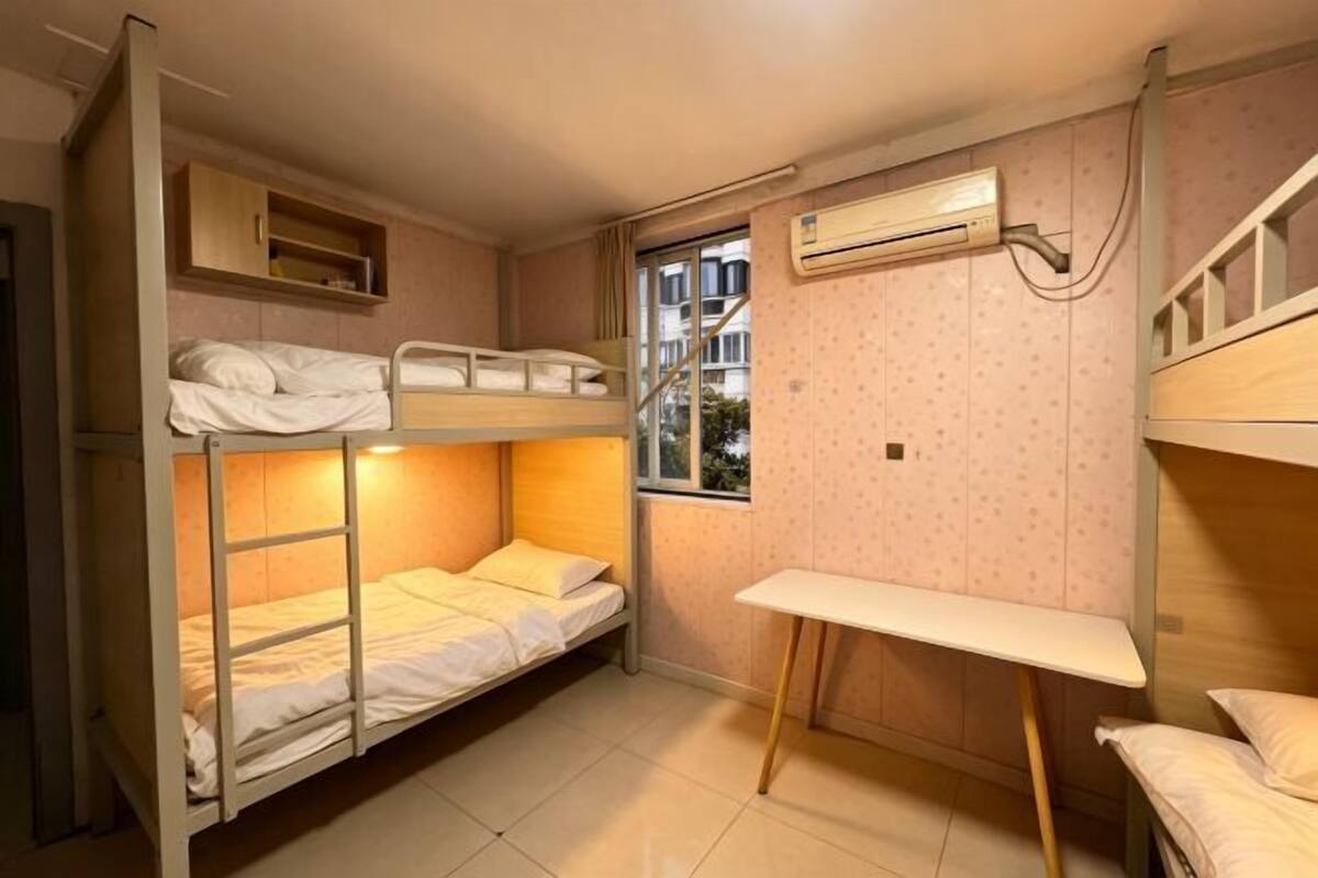 Habitación con literas, escritorio, aire acondicionado y ventana.