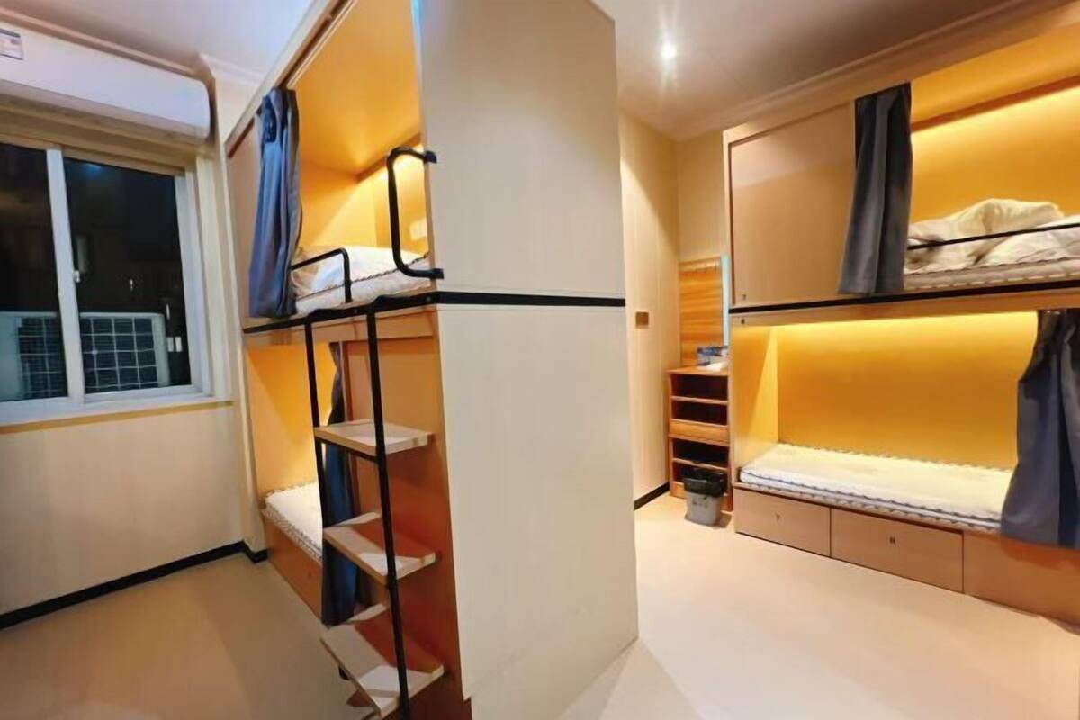 Habitación pequeña con literas, ventana y estanterías integradas.
