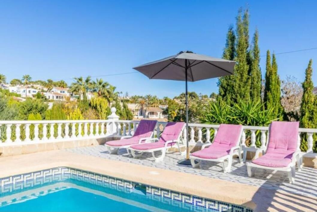 Ein Poolbereich mit Liegestühlen und Sonnenschirm.