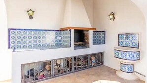 A covered outdoor area with a tiled wall, a chimney, and a metal railing.