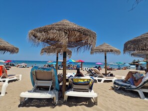 A beach with thatched umbrellas and lounge chairs. - Villa Jacaranda (Teulada)