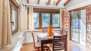 A dining area with a table, chairs, and a window with a view of trees.