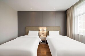 A hotel room with two beds, a wooden floor, a grey wall, and a window with curtains. - Lechao Collection Hotel (Shanghai Bailian Central Zhenguang Road Subway Station) (Shanghai)