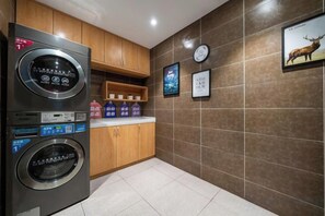 A compact kitchen with a built-in washer and dryer, wooden cabinets, and a tiled backsplash. - Lechao Collection Hotel (Shanghai Bailian Central Zhenguang Road Subway Station) (Shanghai)