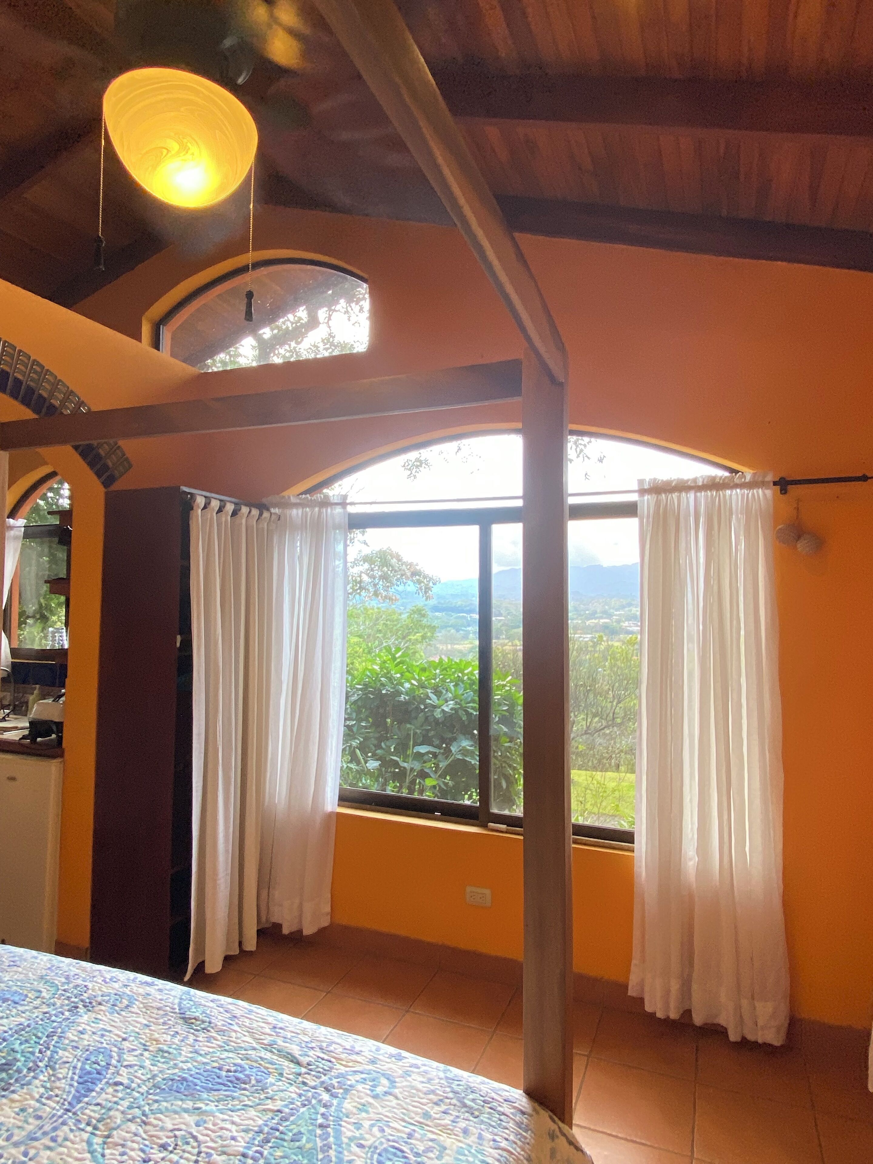 A room with a large window, a bed, and a ceiling light.