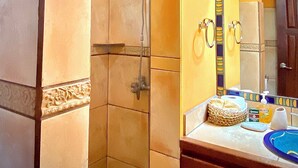 Une salle de bain avec une douche, un lavabo et un miroir. Il y a une pancarte sur le mur avec l’inscription : « Pieds sablonneux, baisers salés ».