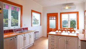 A kitchen with white cabinets, a wooden countertop, and a dining area with a table and chairs. - Napier Hilltop Stays (Napier)
