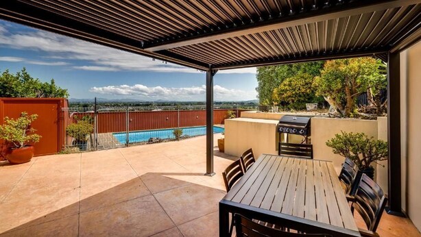 A covered patio with a pool, a barbecue grill, and a dining table with chairs. - Napier Hilltop Stays (Napier)