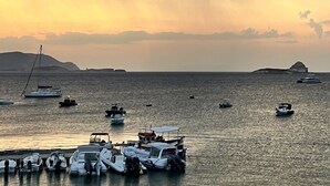 A marina with various boats docked, surrounded by rocky terrain and distant hills. - ZELOS Guesthouse Milos (POLLONIAN)