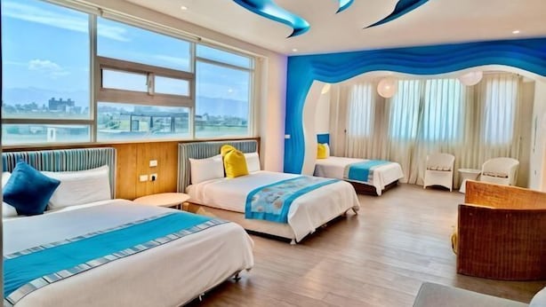 A hotel room with two beds, a desk, and a view of the city. - Tsai Hang B&B (Yilan)