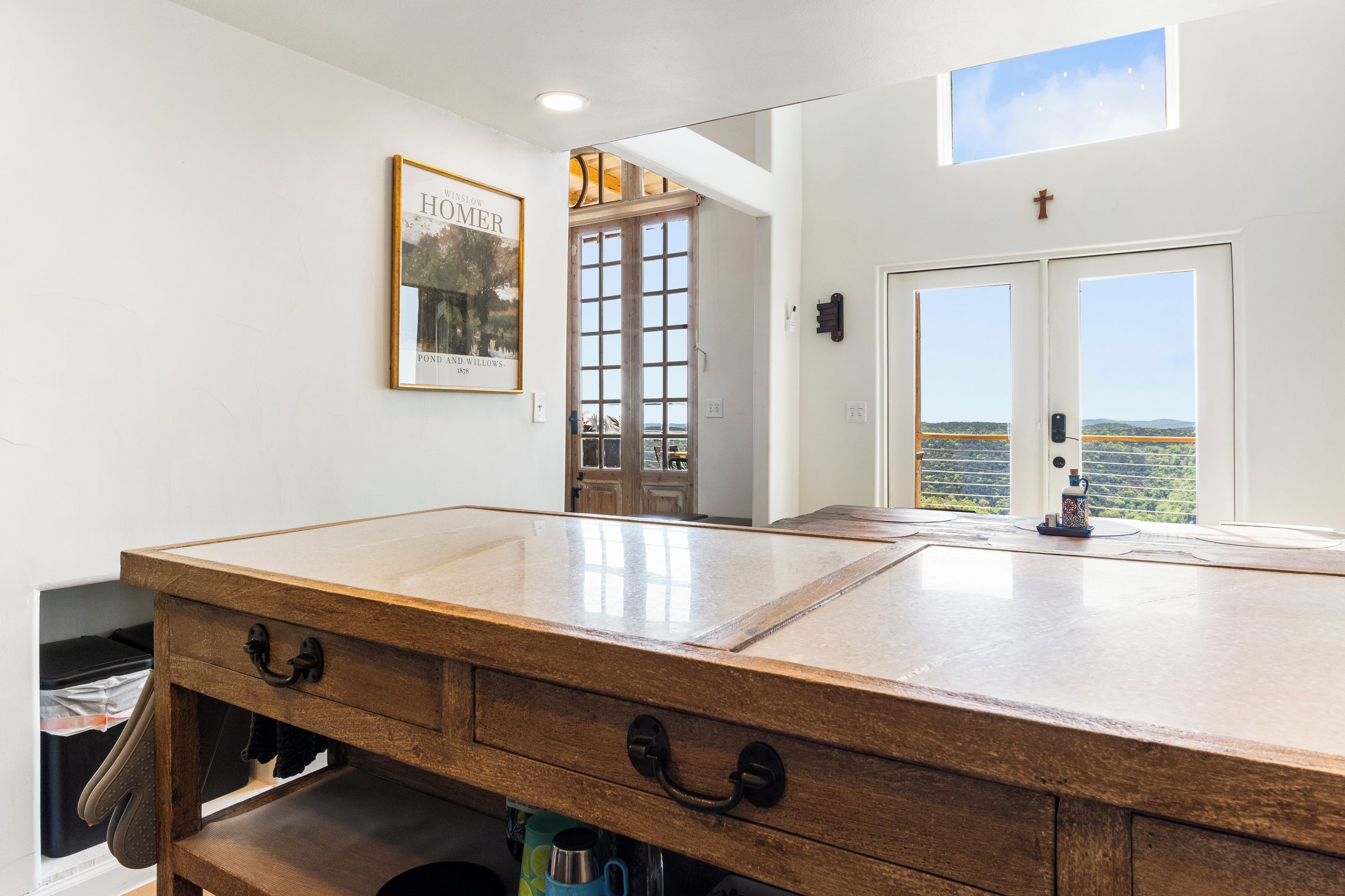 A kitchen with a wooden countertop, a framed picture on the wall, and a view through the door.