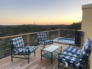 An outdoor deck with a hot tub, lounge chairs, and a view of the landscape. - Carmel in the Sky in Leakey (Leakey)