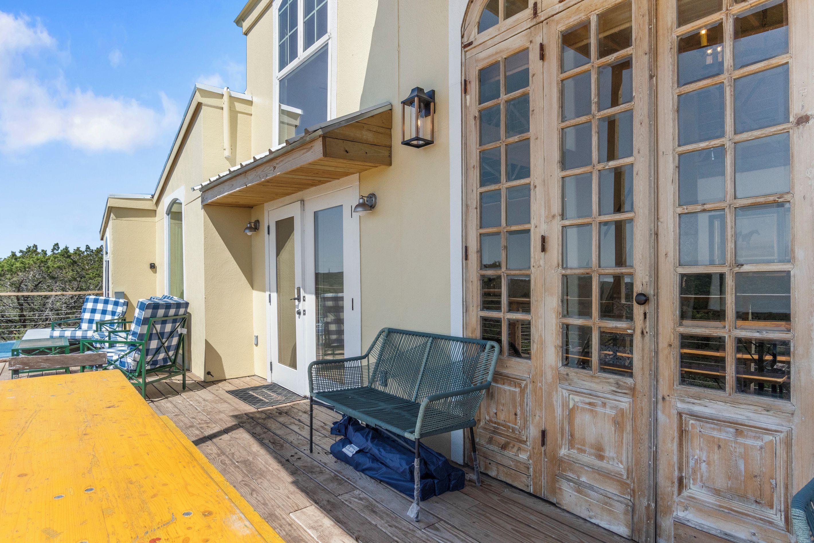 A covered outdoor area with a wooden deck, a bench, and a table with chairs.