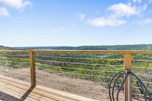 Una terraza de madera con baranda metálica que da a un paisaje montañoso.