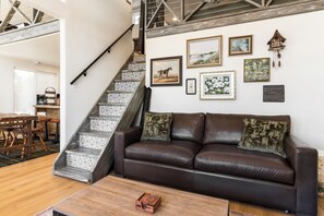 A living room with a brown leather sofa, a wooden coffee table, and a staircase with patterned tiles. - Carmel in the Sky in Leakey (Leakey)