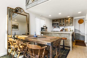 A dining area with a wooden table and chairs, a kitchen with cabinets and appliances, and a large mirror. - Carmel in the Sky in Leakey (Leakey)
