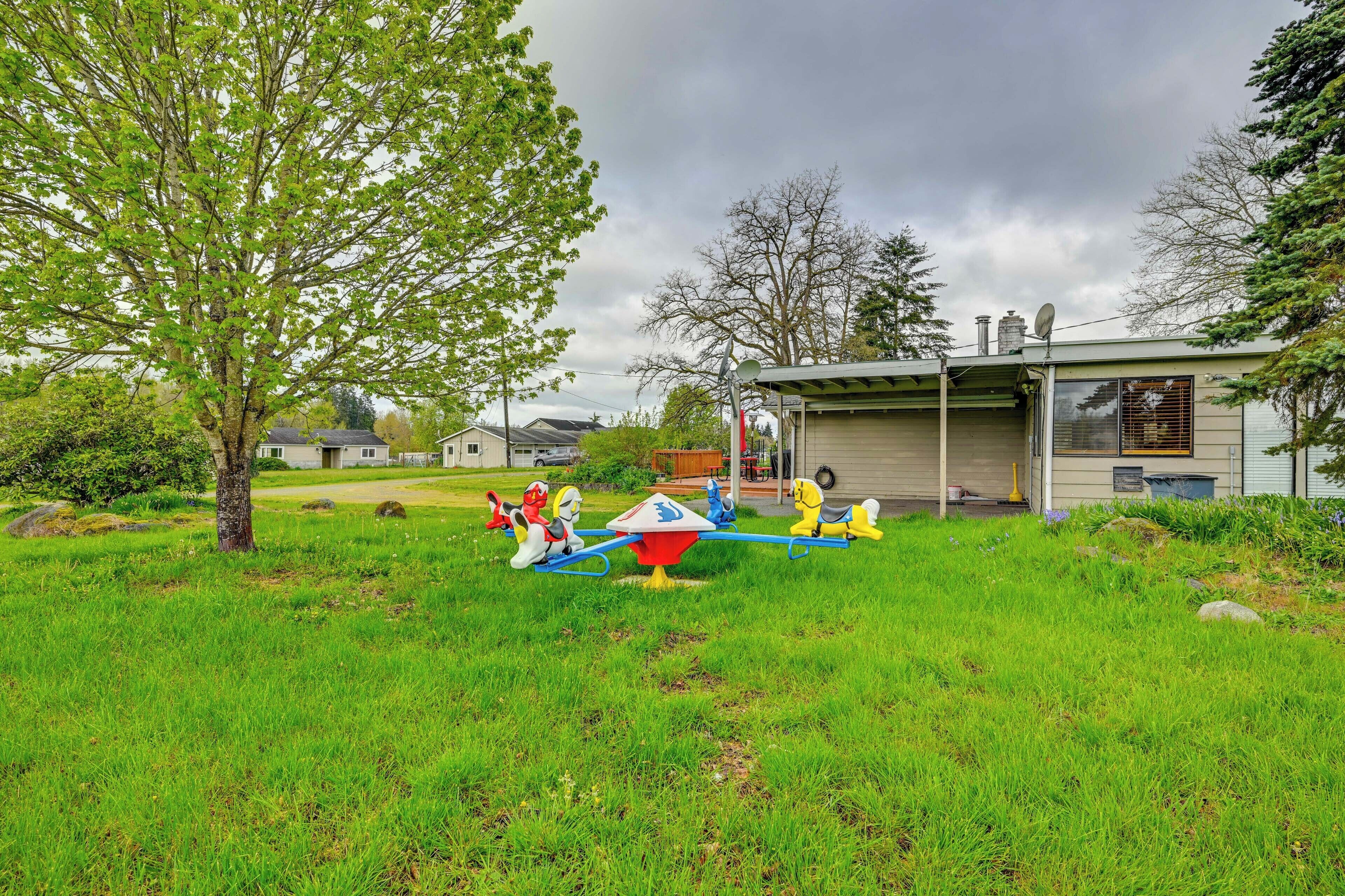 A playground with seesaws and swings, surrounded by grass and trees.