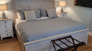 A bedroom with a bed, two bedside tables, a TV, and a wooden floor. - Waterfront 2BR w/ Dock, Hot Tub & Easy Ocean Access – Boaters Welcome! (Marathon)