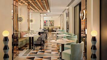 Ein Restaurant mit geometrischem Fußboden, runden Tischen mit Stühlen und modernen Leuchten.