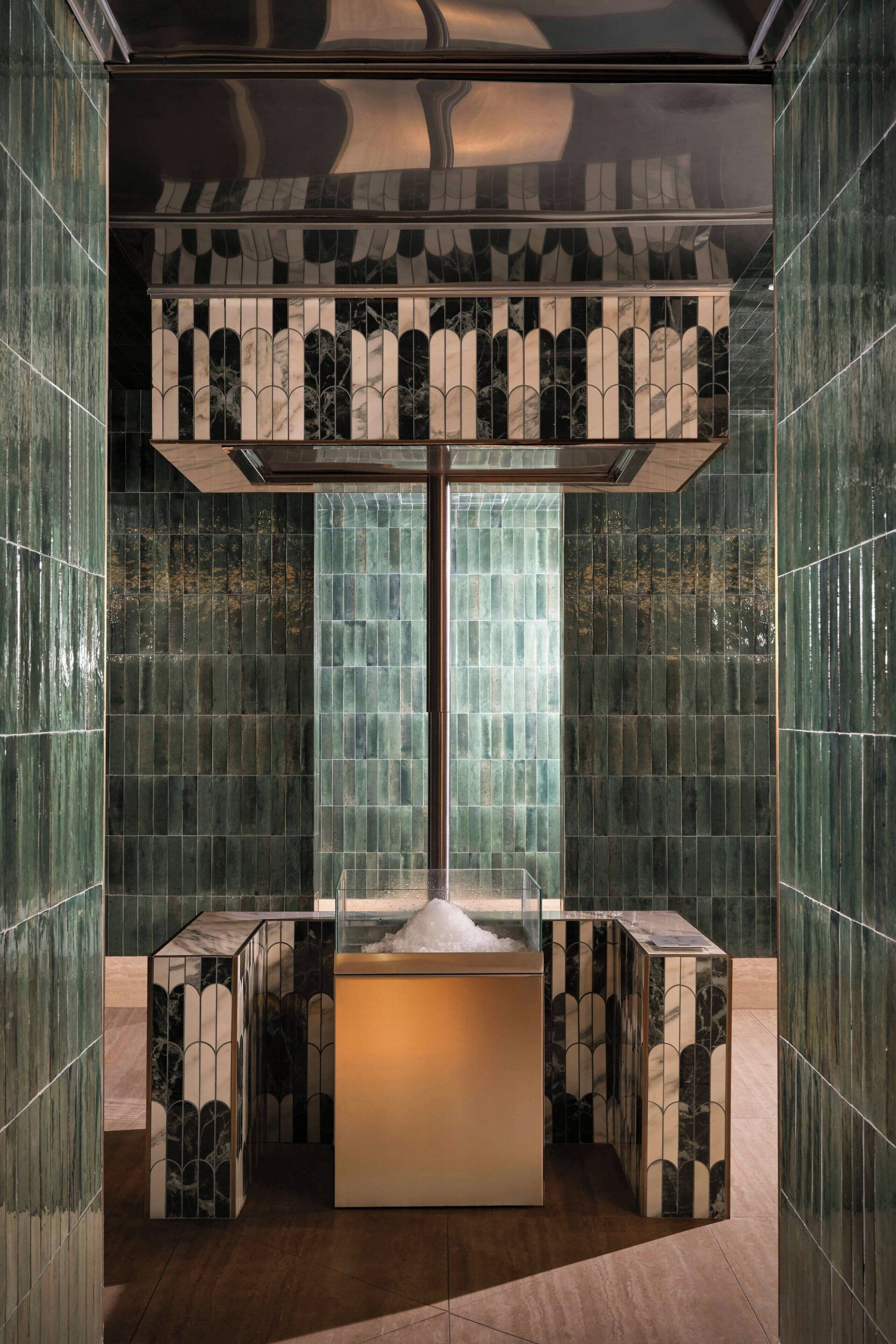 Un bagno moderno con un lavabo centrale, pareti a specchio e un pavimento decorato.