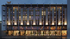 Un hôtel moderne, avec un grand logo en forme de « W », de nombreux étages et une façade bien éclairée.