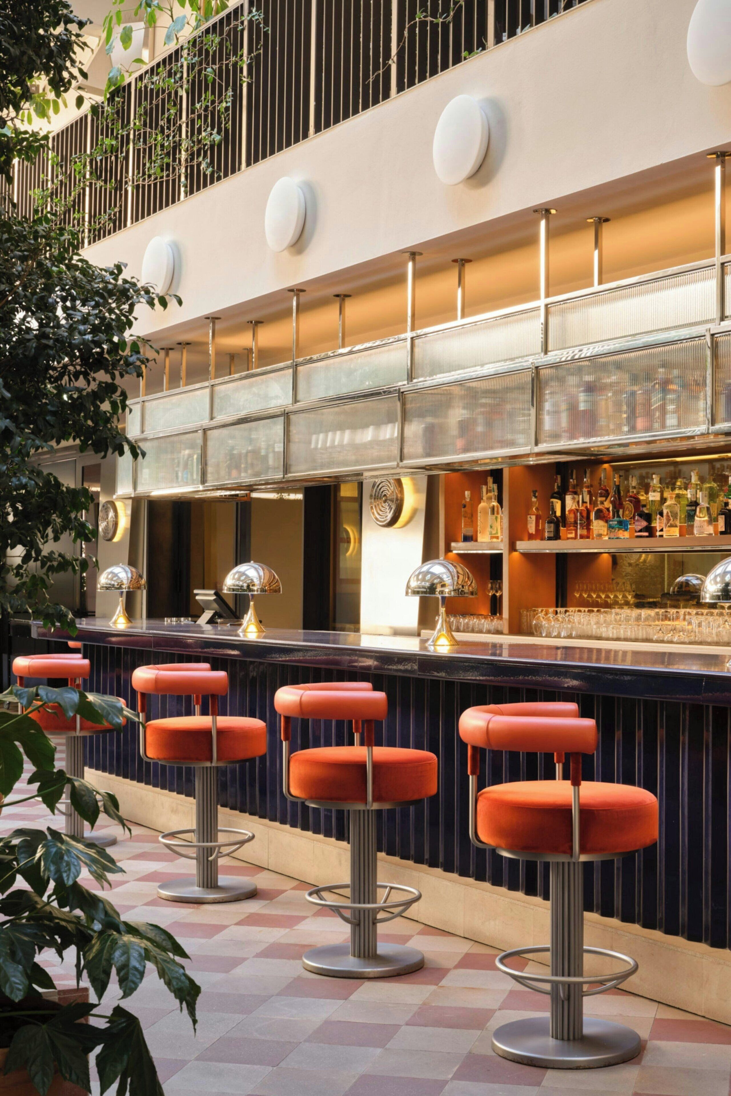 A bar area with a checkered floor, bar stools, and a bar counter with bottles.