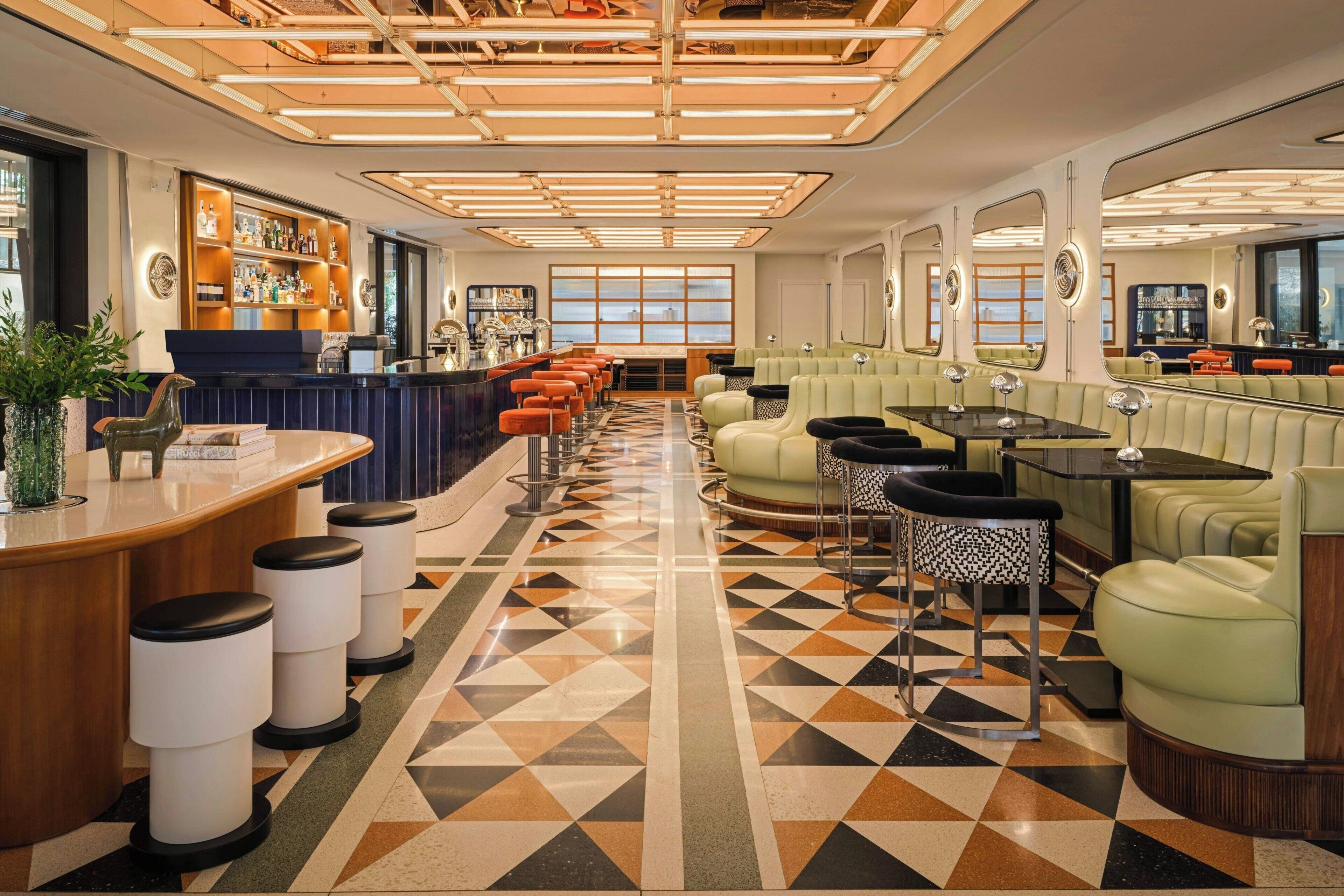 A bar area with stools, a counter, and a seating area with couches and tables.