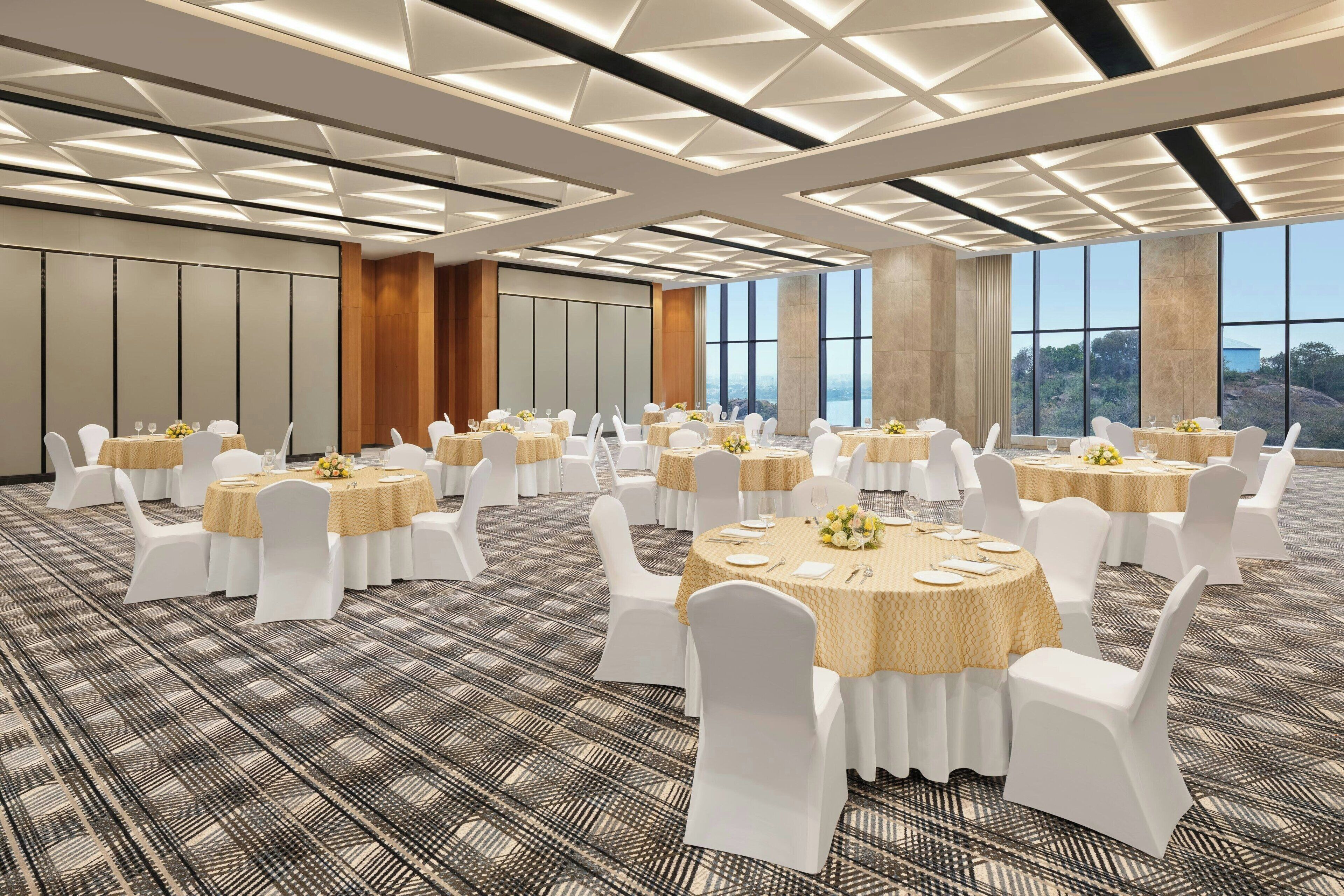A conference room with round tables, white chairs, and a patterned carpet.