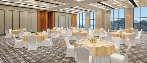 A conference room with round tables, white chairs, and a patterned carpet.