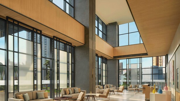 Un lobby espacioso con grandes ventanales, muebles modernos y un techo alto.