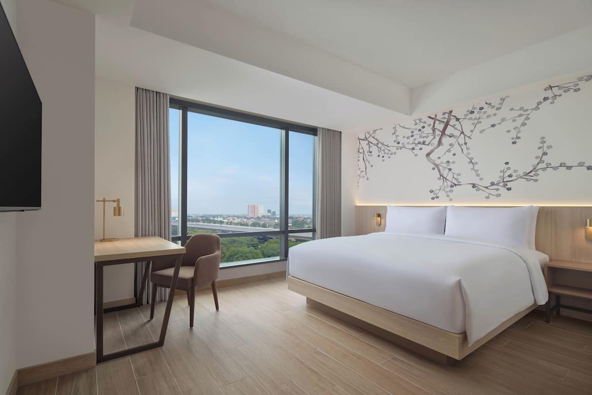 Une chambre d’hôtel moderne, dotée d’un grand lit, d’un bureau et offrant une vue sur la ville.