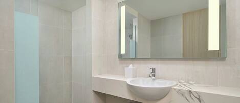 Un bagno moderno con uno specchio grande, un lavabo bianco e un box doccia in vetro.