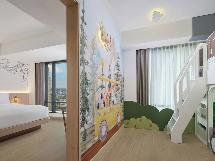 Ein Hotelzimmer mit Bett, Wandgemälde eines Busses, einer Treppe und Blick auf die Stadt.