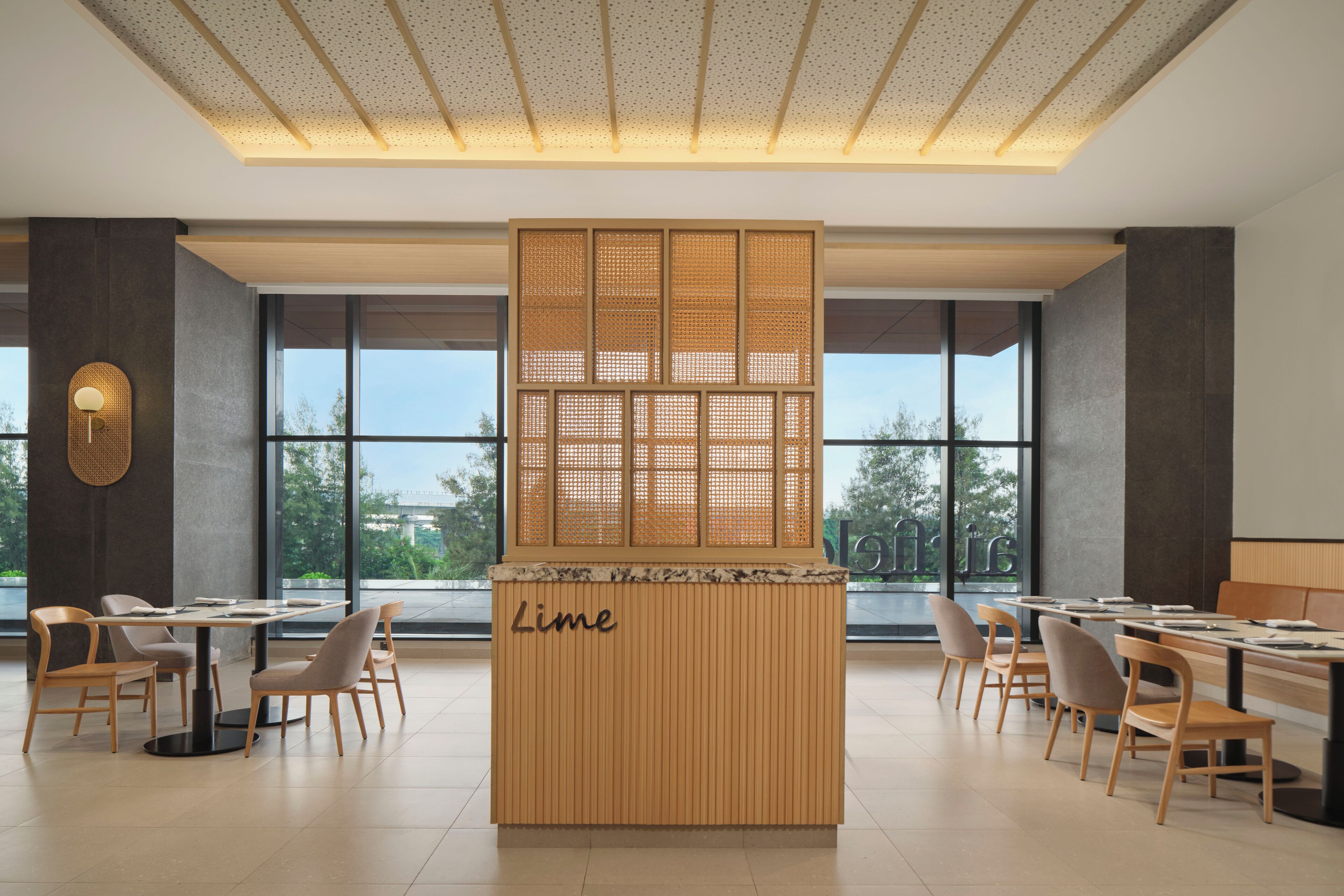 A modern dining area with a central partition labeled "Lime," featuring a wooden design and a perforated screen.