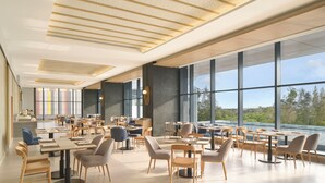 Un comedor espacioso con techos altos, ventanas grandes y mobiliario moderno.