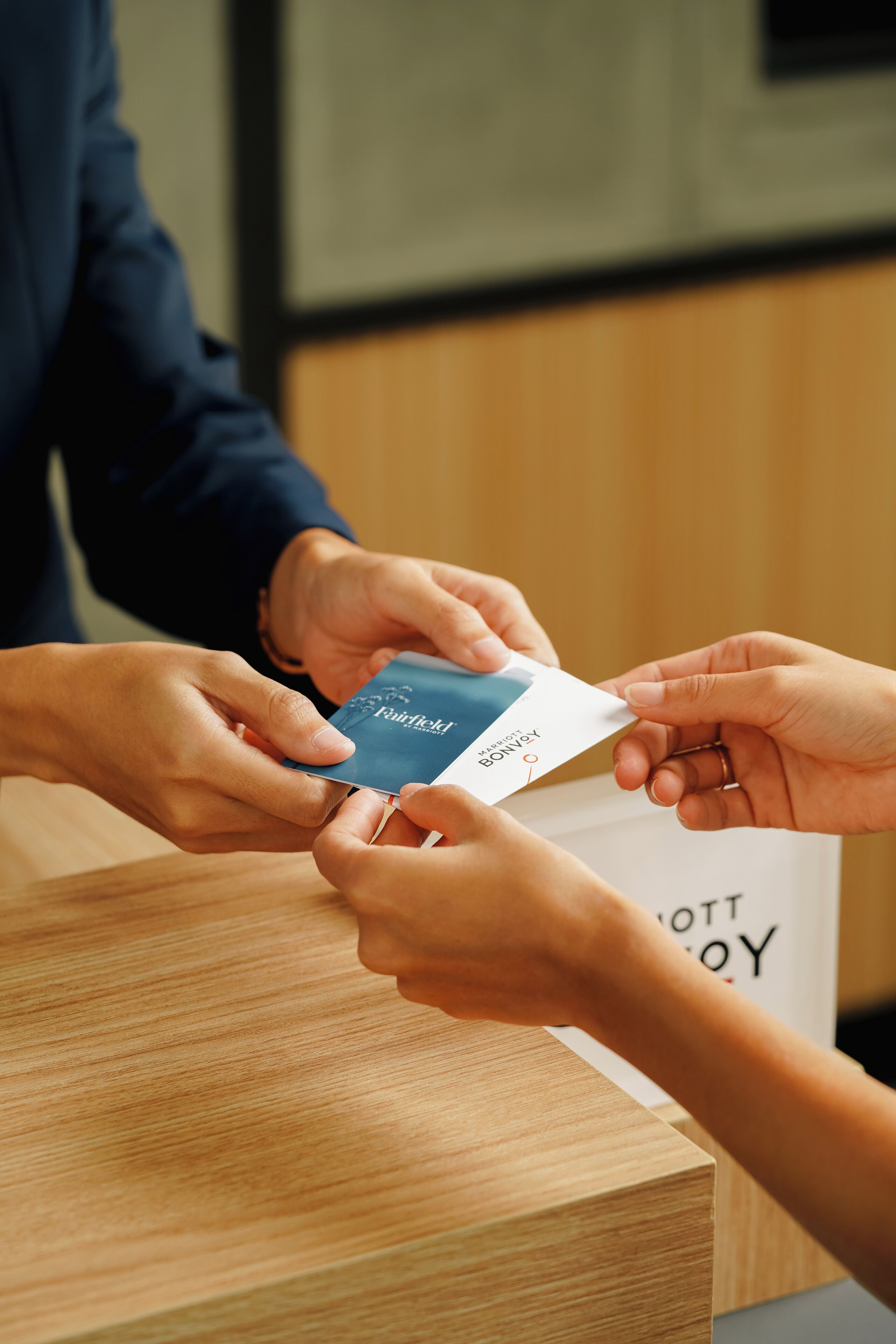 A person handing over a credit card to another individual at a wooden counter.