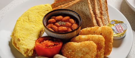 A breakfast plate with toast, beans, sausages, and a glass of orange juice.