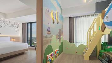 Une chambre d’hôtel avec un grand lit, un espace de jeux pour enfants et une vue sur la ville.