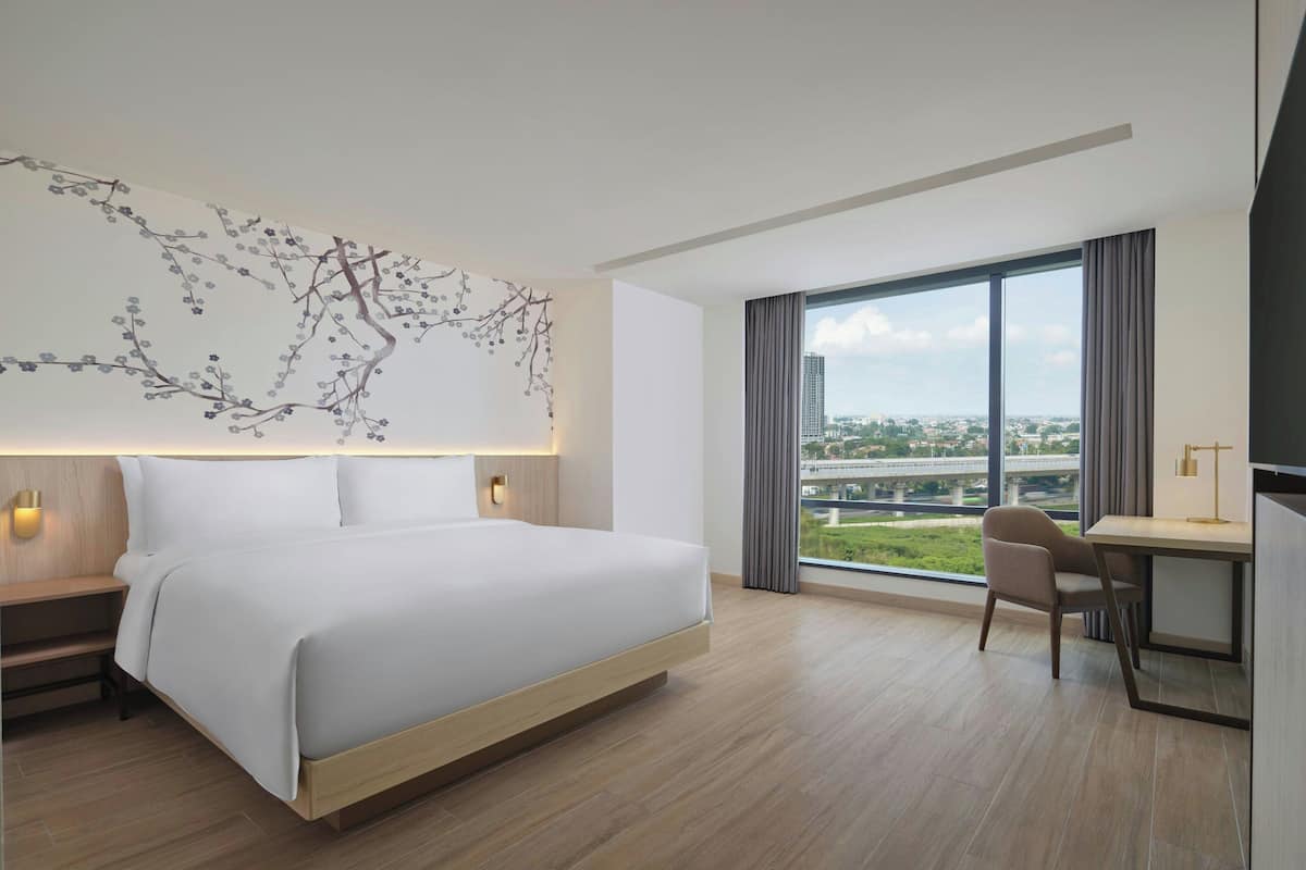 Une chambre d’hôtel moderne, dotée d’un grand lit, d’un bureau et offrant une vue sur la ville.