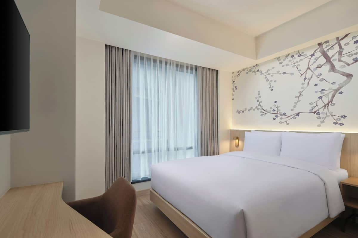 Une chambre d’hôtel moderne, dotée d’un grand lit, d’un bureau et d’une télévision.