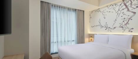 A modern hotel room with a large bed, a desk, and a TV.