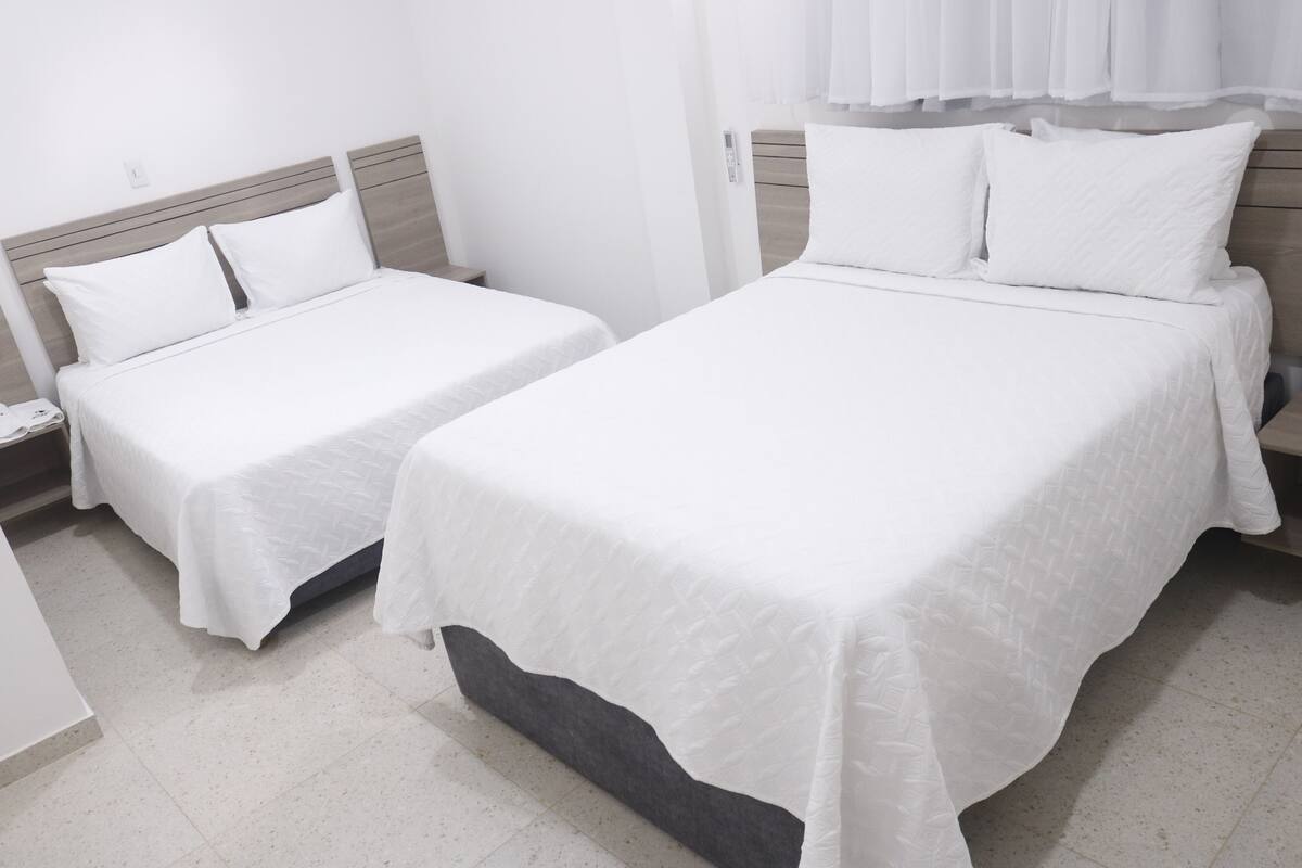 Ett hotellrum med två separata sängar och en större dubbelsäng.