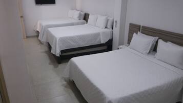 A hotel room with two single beds, a flat-screen TV mounted on the wall, and a door leading to another room.