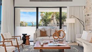 A modern living room with a sofa, chairs, a coffee table, and a view of the ocean. - Villa Maravilla at Pedregal (Cabo San Lucas)